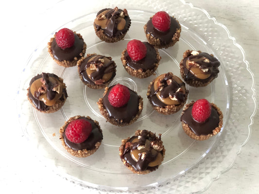 A platter with 12 individual pecan tarts; turtle pecan and raspberry pecan tarts