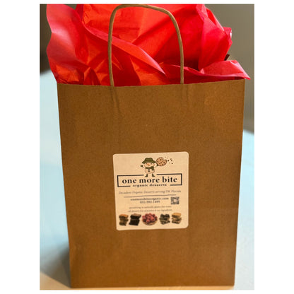 Brown paper bag with red tissue paper and a One More Bite Organic Desserts label.