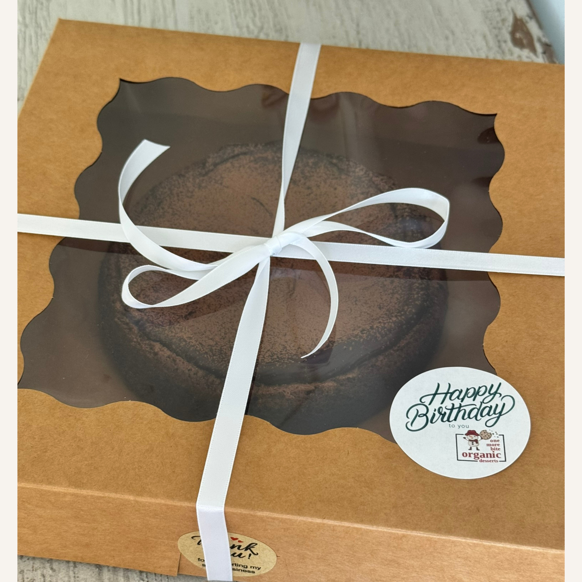 Photo of organic peanut-free chocolate flourless cake with ganache and dusted cooca powder packaged in a birthday gift box– soy-free, corn-free gluten-free dessert handmade in Fort Myers, Florida.
