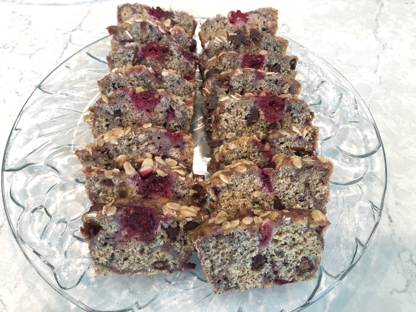 A platter with two loaves of sliced Oatmeal Banana Raspberry Chocolate Chip Bread